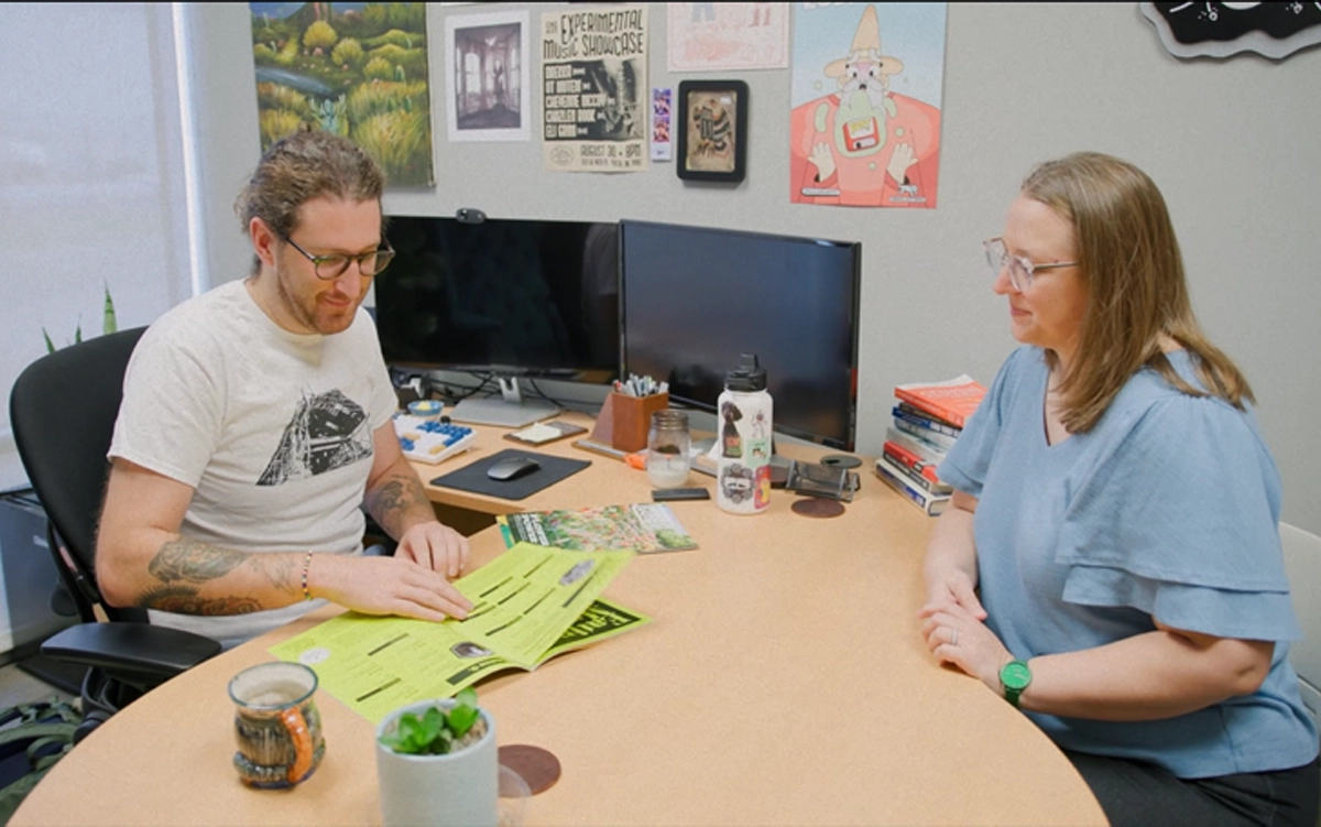 Man and woman look at brochure in an office space.